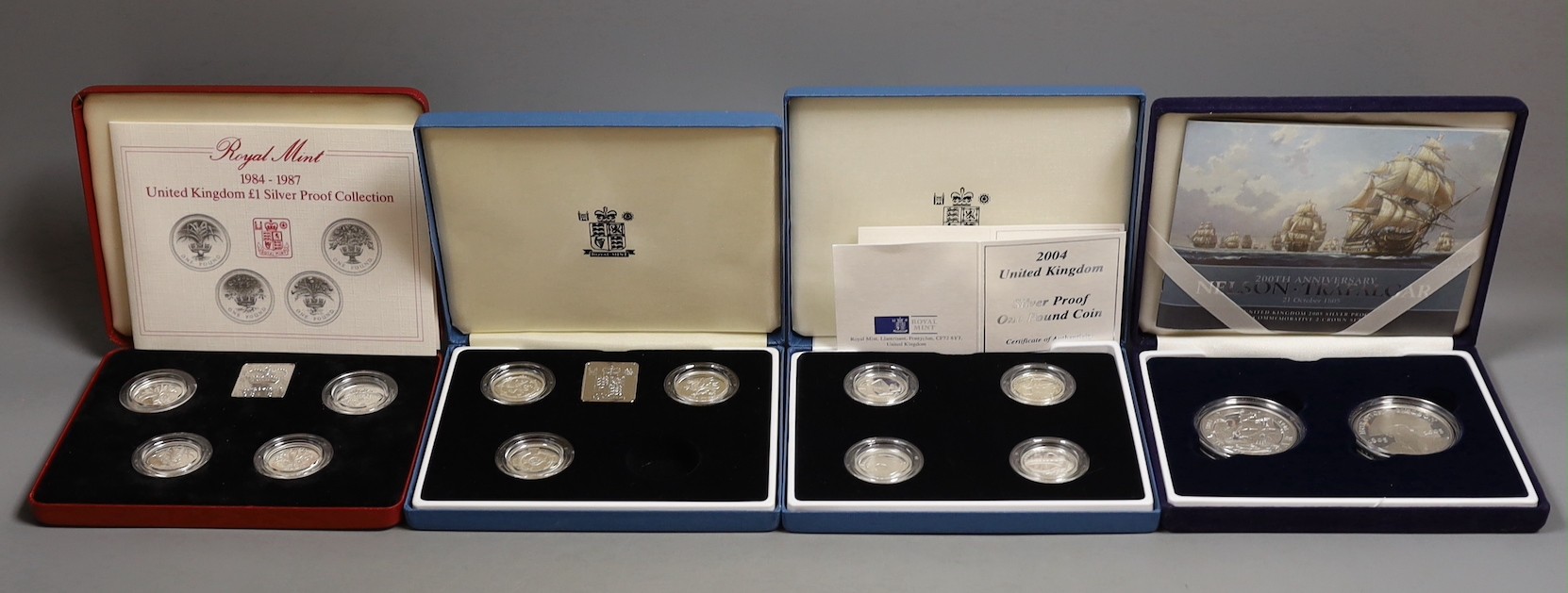 Three cased Royal Mint UK silver proof £1 coin collections 1984-87, 1994-96, 2004-07 and a 200th anniversary Nelson Trafalgar 2005 silver proof two crown set